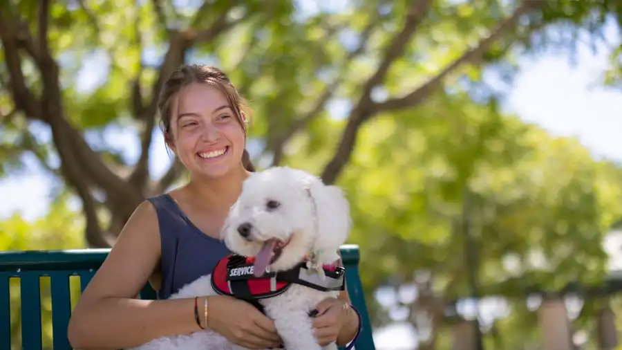 Smiling woman on a park bench with her small service dog